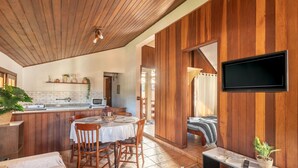 A modern kitchen with a wooden ceiling, a dining area with a table and chairs, and a TV mounted on the wall. - Lovely House in Campos do Jordao Mcd001 (Campos do Jordão)