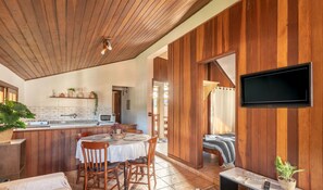 A modern kitchen with a wooden ceiling, a dining area with a table and chairs, and a TV mounted on the wall. - Lovely House in Campos do Jordao Mcd001 (Campos do Jordão)