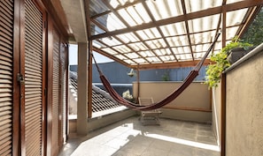 A covered outdoor area with a hammock, a chair, and a potted plant. - Lovely House in Campos do Jordao Mcd001 (Campos do Jordão)