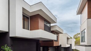 A modern multi-story residential building with a flat roof, large windows, and a combination of white and wooden paneling. - The Treetop Townhouse in Templestowe (Templestowe Lower)