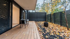 An outdoor patio with a wooden deck, a table, and chairs. - The Treetop Townhouse in Templestowe (Templestowe Lower)