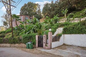 A residential property with a gated entrance, a brick wall, and a hillside with vegetation. - Hollywood Hills Cabin at Wonderland Canyon (Los Angeles)