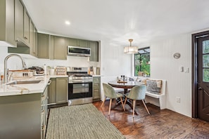 A modern kitchen with a central island, built-in appliances, and a dining area with a round table and chairs. - Hollywood Hills Cabin at Wonderland Canyon (Los Angeles)