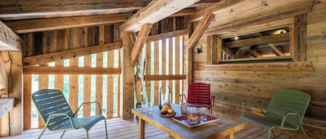 A wooden cabin interior with a dining table, chairs, and a window.