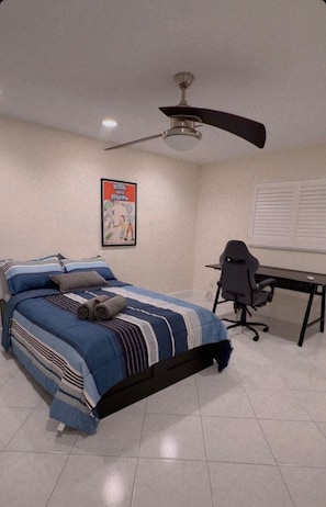 A bedroom with a bed, a desk, a chair, a ceiling fan, and a poster on the wall. - Beach House in Indian Rocks Beach | 4 bedrooms with pool (Indian Rocks Beach)