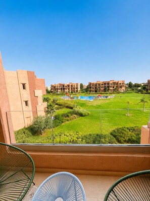 A hotel balcony with a view of a swimming pool and greenery. - 2-bedroom apartment, 2 pools, Golf Prestigia Jubaea (Marrakesh)