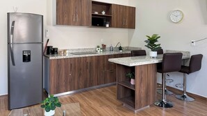 Uma cozinha moderna com frigorífico embutido, armários de madeira, bancada de granito e uma pequena ilha com banquetas.