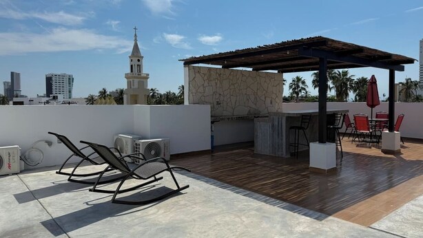 Terraço no terraço com pérgola, mobiliário e vista para o horizonte da cidade.