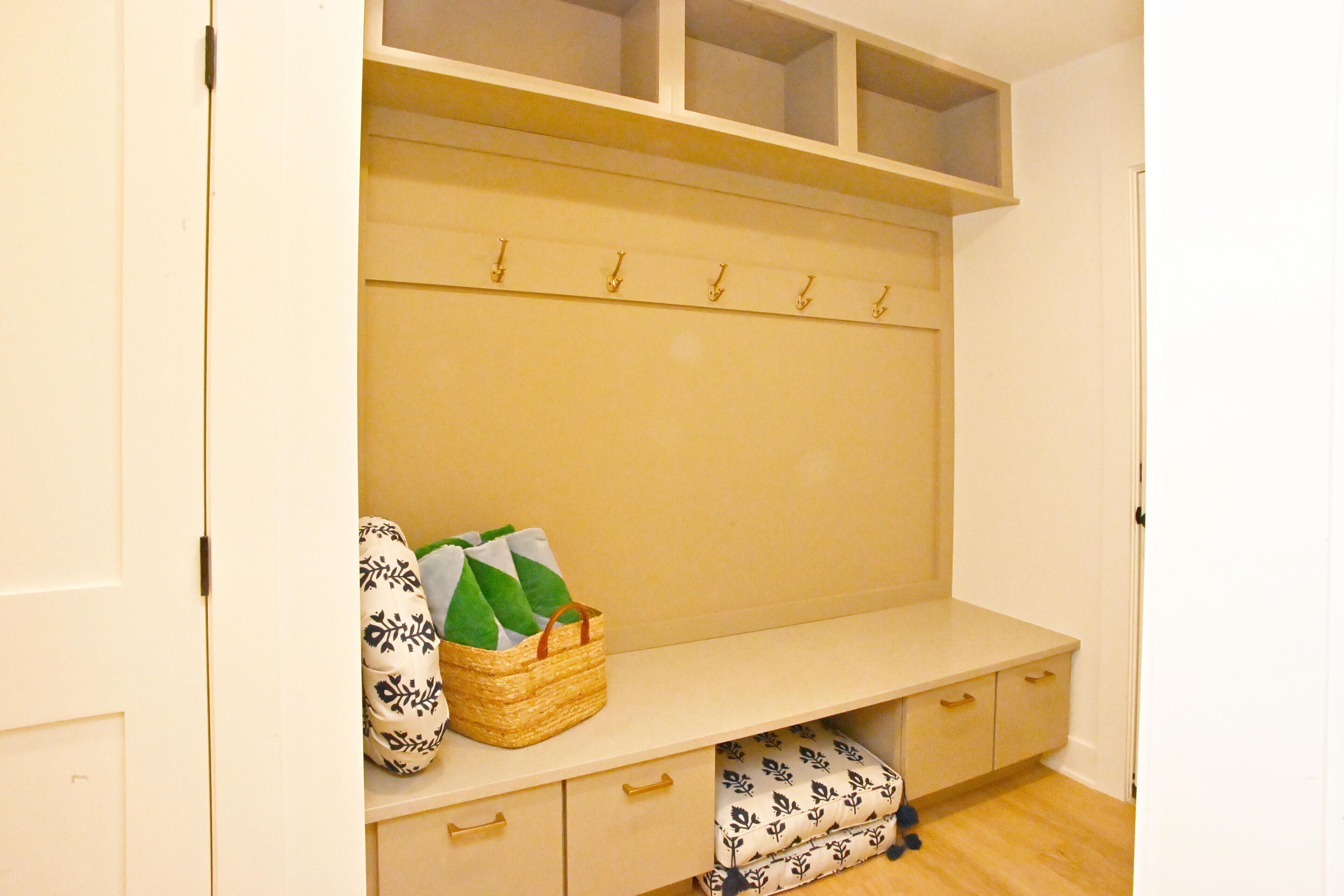 A room with a bench, hooks, and storage drawers.