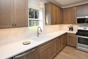 A modern kitchen with wooden cabinets, a stainless steel range, and a built-in oven.