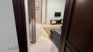 Un umbral abierto que da a una sala de estar con televisor de pantalla plana, un sofá y una alfombra.