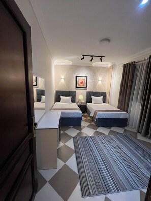 Una habitación de hotel con dos camas, un escritorio y un mostrador de recepción.