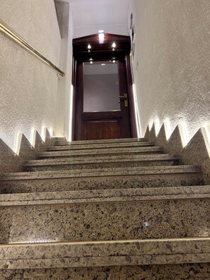 Eine Treppe mit Handlauf führt zu einer Holztür mit einer Glasscheibe.