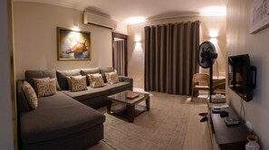 Ein Wohnzimmer mit einer Couch, einem Couchtisch, einem Fernseher und einem Ventilator.