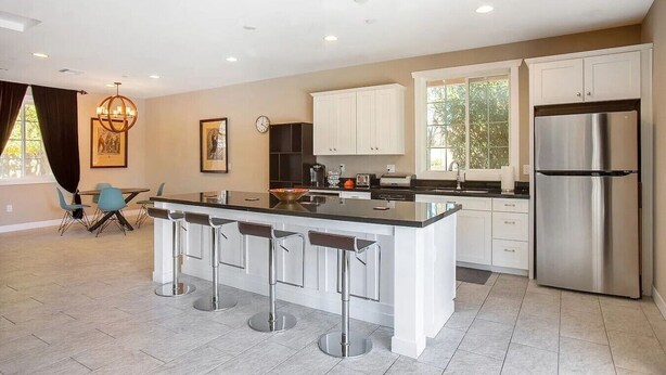 A modern kitchen with white cabinets, a stainless steel refrigerator, and a bar area with stools. - Private Scottsdale Oasis - Pool, Spa & Casita (Scottsdale)