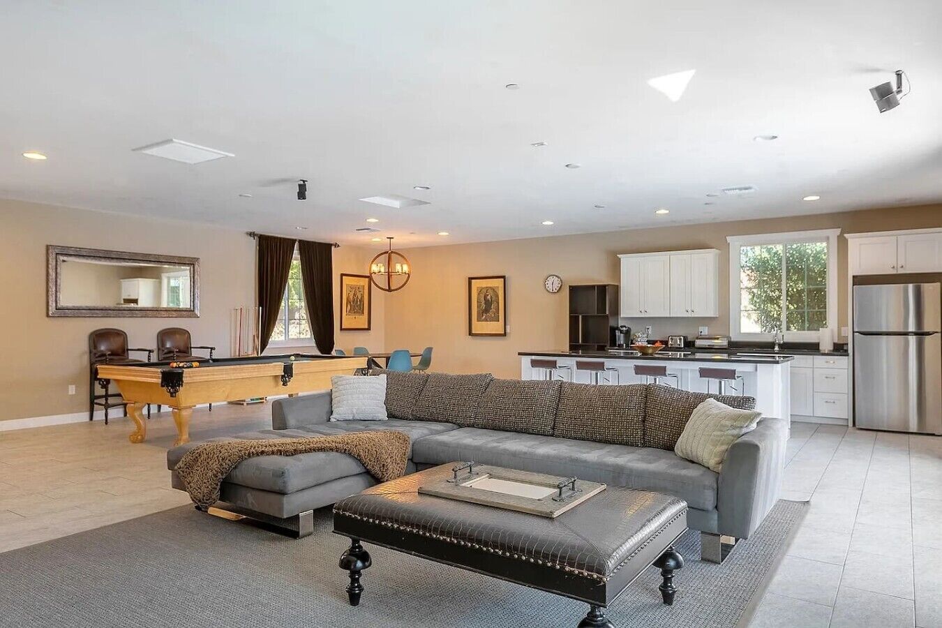 Un salon moderne avec un canapé, un pouf et une table de billard.