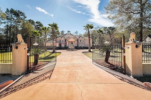 A gated entrance to a property with a paved driveway leading to a building. - Sleeps 16 | Pool + Slide | Family Retreat (Porter)