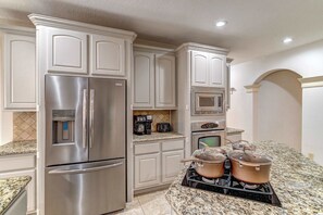 A kitchen with stainless steel appliances, granite countertops, and white cabinetry. - Sleeps 16 | Pool + Slide | Family Retreat (Porter)