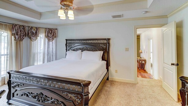 A bedroom with a large bed, a ceiling fan, and a door leading to another room. - Sleeps 16 | Pool + Slide | Family Retreat (Porter)