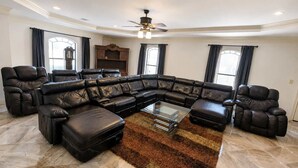 A spacious living room with a large L-shaped sectional sofa, a glass coffee table, and a ceiling fan. - Sleeps 16 | Pool + Slide | Family Retreat (Porter)