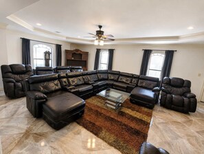A spacious living room with a large L-shaped sectional sofa, a glass coffee table, and a ceiling fan. - Sleeps 16 | Pool + Slide | Family Retreat (Porter)