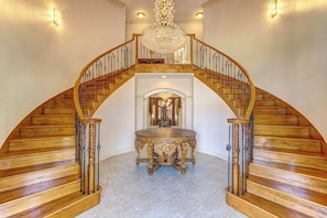 A grand staircase with a chandelier, leading to an upper level. - Sleeps 16 | Pool + Slide | Family Retreat (Porter)