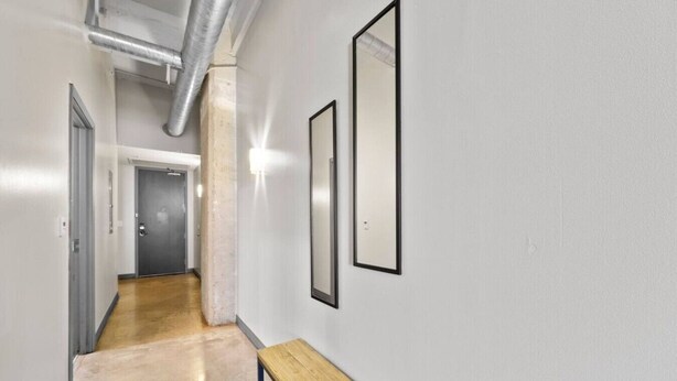 A hallway with a bench, a door at the end, and two framed pictures on the wall. - Downtown Dallas Haven | Pool + Theater + Game Room (Dallas)