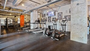 A gym with treadmills, elliptical machines, and weightlifting equipment. - Downtown Dallas Haven | Pool + Theater + Game Room (Dallas)