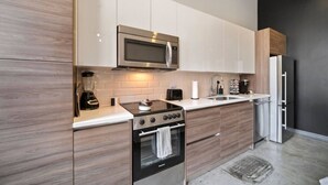A modern kitchen with a built-in microwave, stove, and refrigerator. - Downtown Dallas Haven | Pool + Theater + Game Room (Dallas)