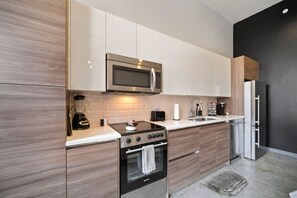 A modern kitchen with a built-in microwave, stove, and refrigerator. - Downtown Dallas Haven | Pool + Theater + Game Room (Dallas)