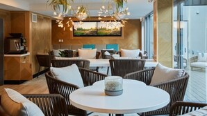 A modern interior with wicker furniture, a round table, and a large flat-screen TV mounted on the wall. - Mi-pad Smart Hotel (Queenstown)
