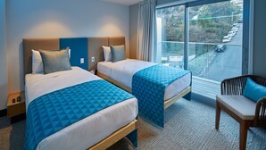 A hotel room with two beds, a window with a view of a road, and a chair. - Mi-pad Smart Hotel (Queenstown)