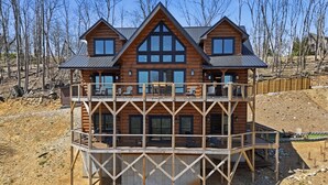 Eine zweistöckige Holzhütte mit Balkon und mehreren Fenstern.