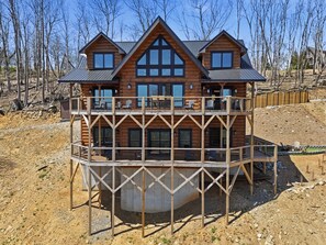 Eine zweistöckige Holzhütte mit Balkon und mehreren Fenstern.