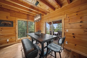 A wooden interior with a dining table, benches, and a large window. - Grandfather Mountain Views, Hot Tub, Game Room & Putting Green (Seven Devils)