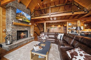Ein rustikales Blockhaus-Interieur mit Kamin aus Stein, einer Ledersofa und einem Essbereich.