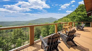 Eine Holzterrasse mit Sitzgelegenheiten und Blick auf eine Berglandschaft.