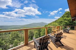 Eine Holzterrasse mit Sitzgelegenheiten und Blick auf eine Berglandschaft.