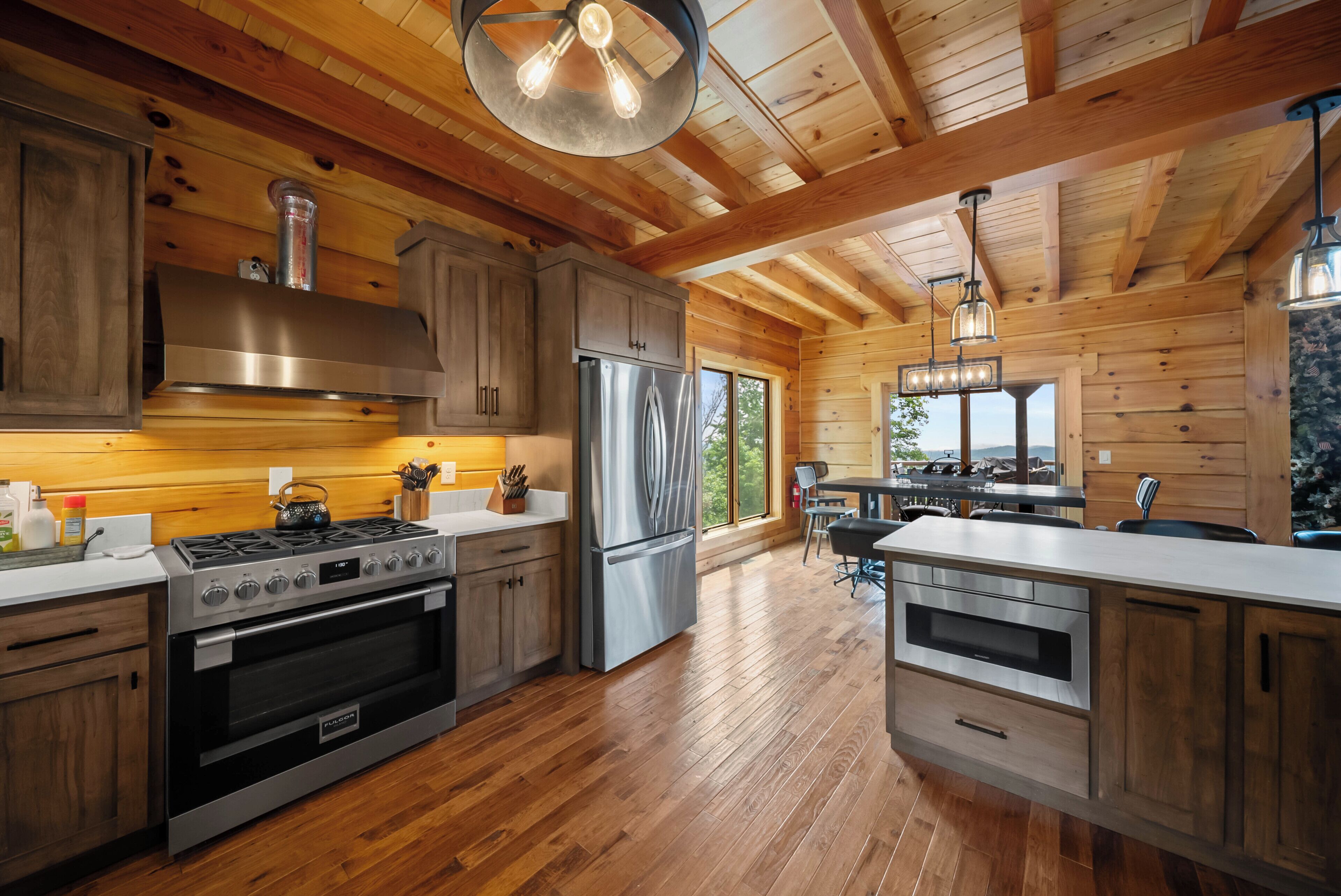 A modern kitchen with wooden cabinetry, stainless steel appliances, and a large window.
