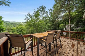 A wooden deck with a table and chairs, overlooking a forested valley. - Cozy 2BR retreat near Beech Mountain Resort. (Beech Mountain)