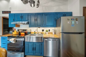 A kitchen with blue cabinets, stainless steel appliances, and a refrigerator with magnets. - Cozy 2BR retreat near Beech Mountain Resort. (Beech Mountain)