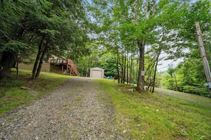 A gravel path leading to a wooden deck and a small building, surrounded by dense trees. - Cozy 2BR retreat near Beech Mountain Resort. (Beech Mountain)