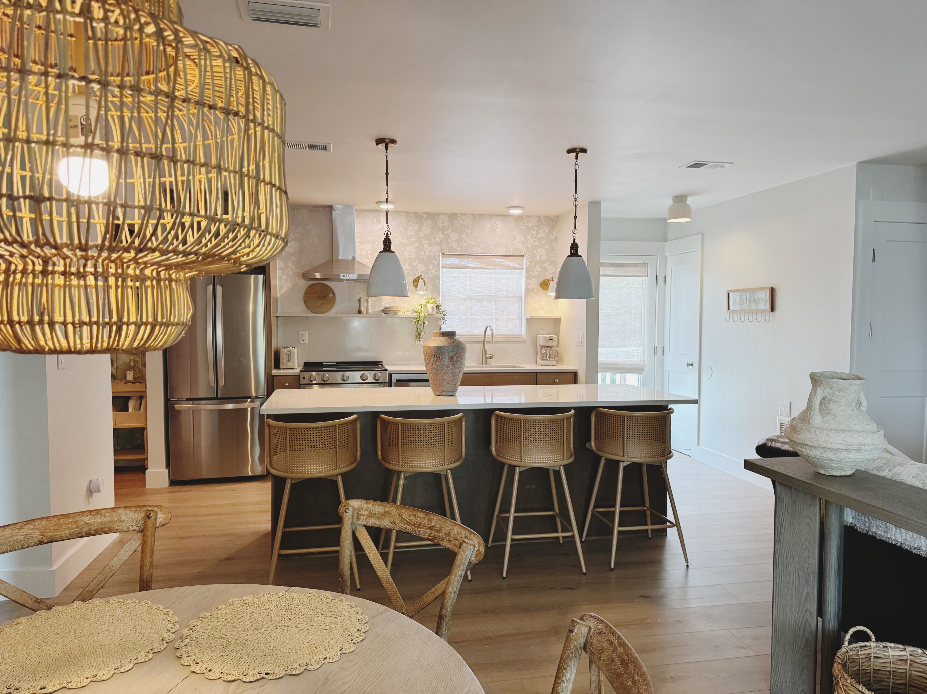 A modern kitchen with a central island, bar stools, and pendant lighting.