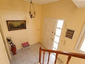 Un couloir avec une porte, un tableau, un vase et une chaise.
