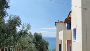 Un edificio costero con balcón que da al mar, rodeado de vegetación.