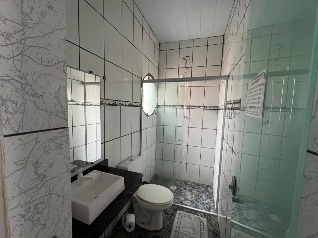 Un baño con inodoro blanco, lavabo y zona de ducha.