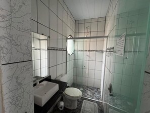 Un baño con inodoro blanco, lavabo y zona de ducha.