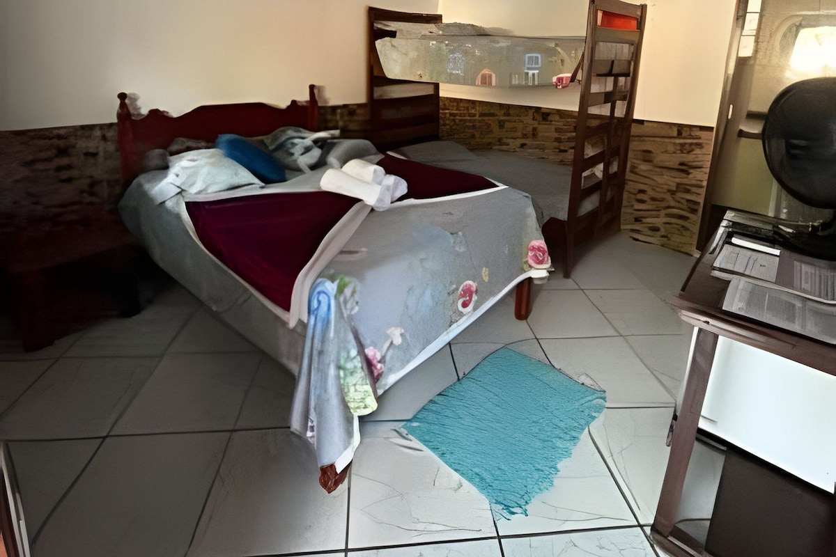 A bedroom with a bed, a desk, and a mirror.