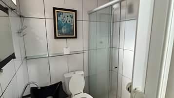 Casa de banho com sanita, cabine de duche em vidro e lavatório com bancada preta.