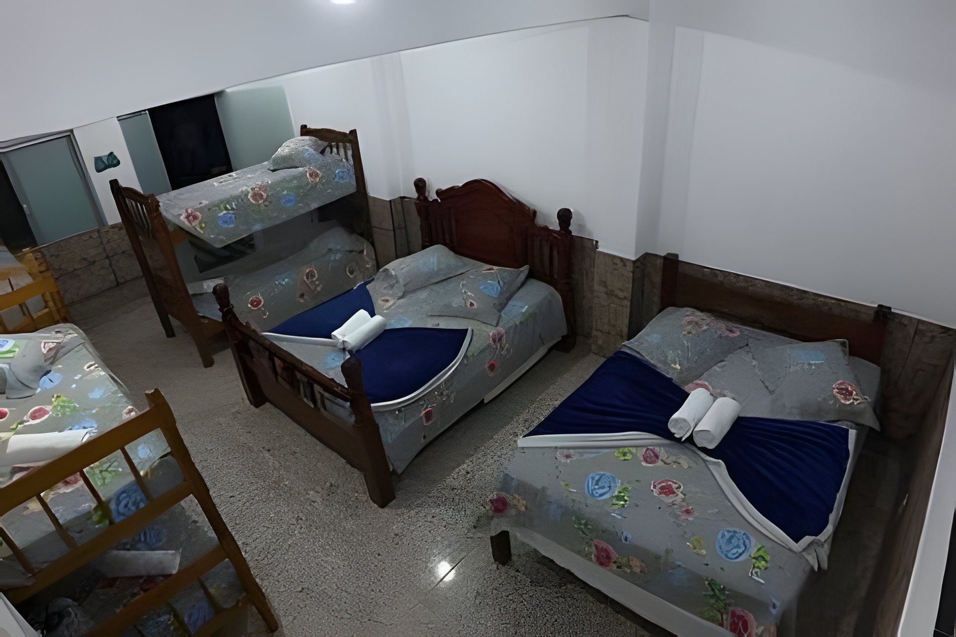 Quarto com três beliches, uma cadeira de madeira e uma mesa pequena.